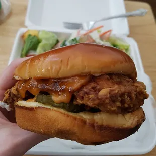 a hand holding a chicken sandwich