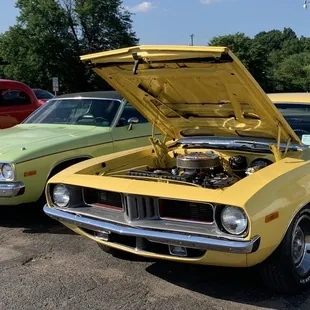 two classic muscle cars parked in a parking lot