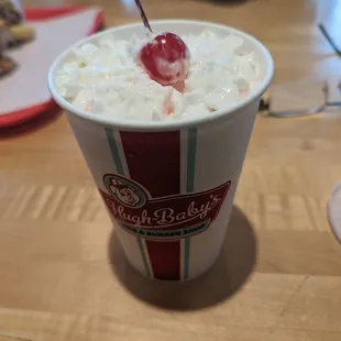 a cup of milkshake with a cherry on top