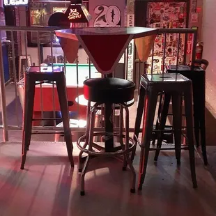a bar with stools and neon signs
