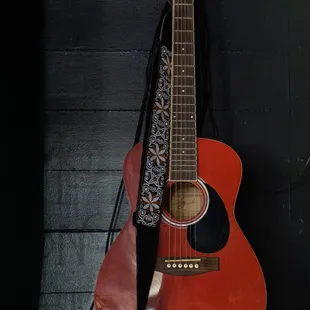 a red acoustic guitar hanging on a wall