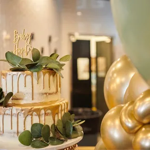 a three tiered cake with gold drips and greenery