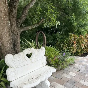 a white bench in front of a tree