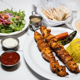 chicken skewers, rice, and salad