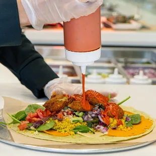 a person putting ketchup on a tortilla