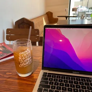 a glass of iced tea next to a laptop