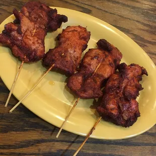 chicken skewers on a yellow plate
