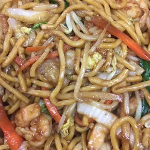 a plate of noodles with shrimp and vegetables