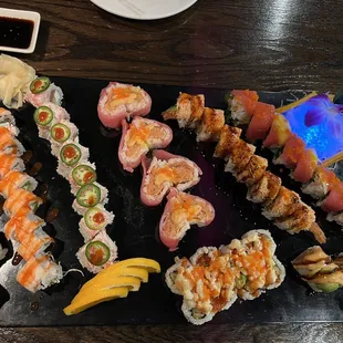a variety of sushi on a black plate