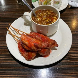 a bowl of soup and skewered meat