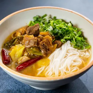 a bowl of noodles with meat and vegetables