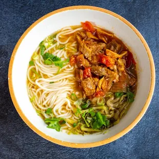 a bowl of noodles with meat and vegetables