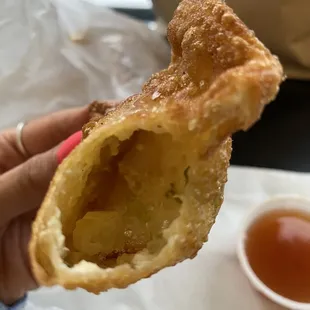 a hand holding a pastry with a bite taken out of it