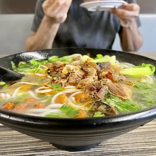 a man eating a bowl of noodles