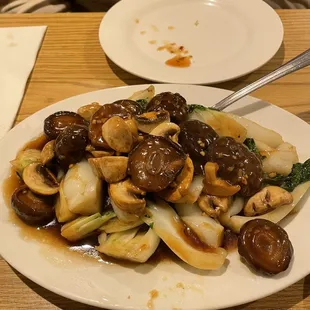 a plate of stir fried mushrooms and broccoli