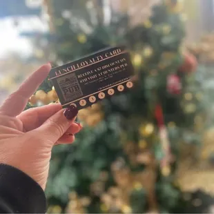a person holding a ticket in front of a christmas tree