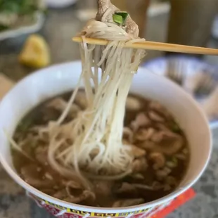a bowl of noodles with chopsticks