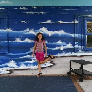 a woman standing in front of a painted wall