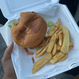 a burger and fries in a styrofoam container