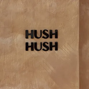 the word hush hush written on a wall