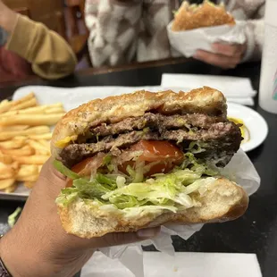 a hand holding a sandwich with meat and lettuce