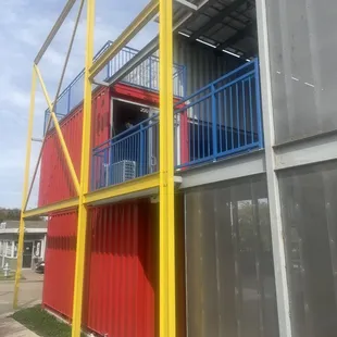 a red and yellow building with a blue balcony