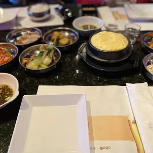 Side dishes including steamed egg in a stone hot pot