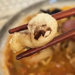 a bowl of soup with chopsticks