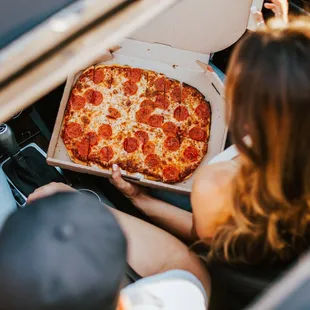 a woman holding a box of pizza