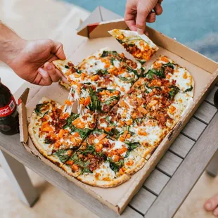 a person taking a slice of pizza