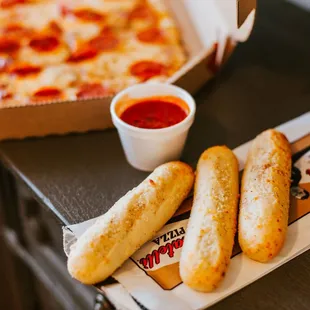 a box of pepperoni pizza and two hot dogs