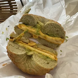a bagel sandwich with cheese and avocado