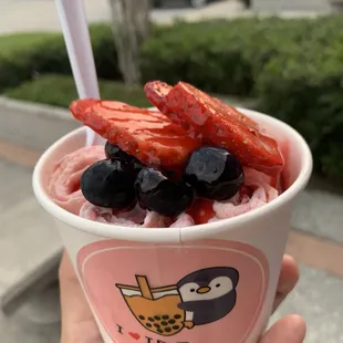 strawberry ice cream with strawberry syrup, strawberries, and blueberries on top