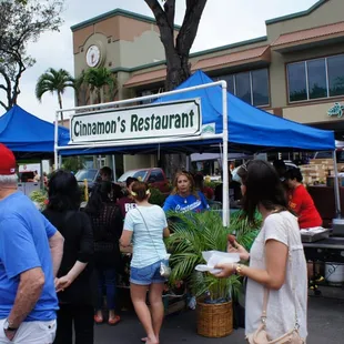 a group of people standing under a blue tent