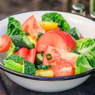 a bowl of salad with tomatoes and broccoli