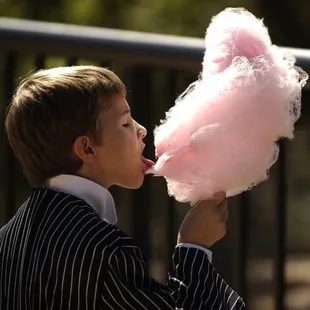 a young boy eating a cotton candy floss