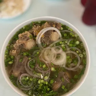 a bowl of soup with meat and onions