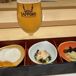 a glass of beer and three bowls of food