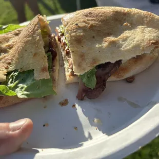 a half eaten sandwich on a paper plate