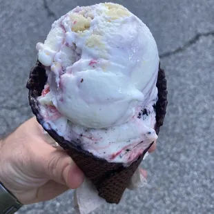 Chocolate waffle cone with kitty kitty bang bang on bottom and blackberry lemon bar on top