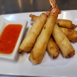a plate of fried spring rolls with dipping sauce
