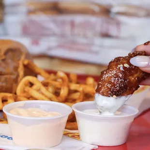 a person dipping a piece of fried chicken