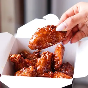 a hand holding a piece of chicken wings