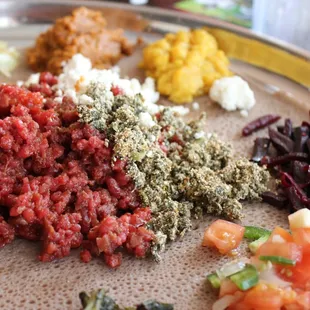 Kitfo is the steak tartare of Ethiopia, the gomen kitfo is the greens with cheese to the right, and delicious beets.