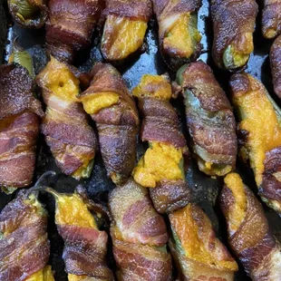 Jalapeño poppers. Jalapeño halves stuffed with a tomato, onion, garlic, and cheddar blend, wrapped in bacon, and slow smoked.