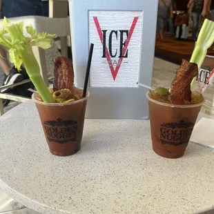two cups of bloody drink with celery in them