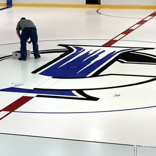 Painting the Ice Castle logo at center ice