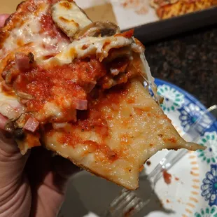 a hand holding a slice of pizza