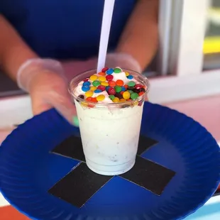 a person holding a paper plate with a cup of ice cream