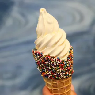 a hand holding an ice cream cone with sprinkles